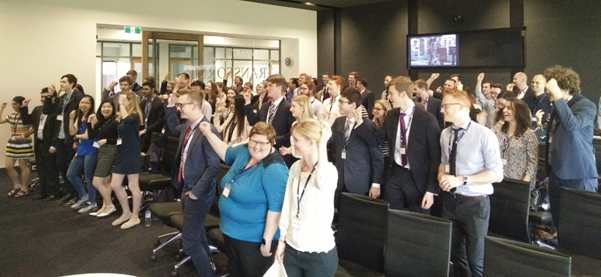 A group of people standing within an office, fists raised in air, for the Nudgeathon.